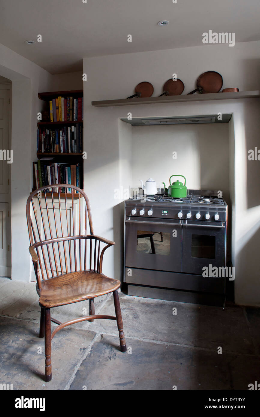 Period chair in front of range oven in basement kitchen, Whitechapel, London Stock Photo