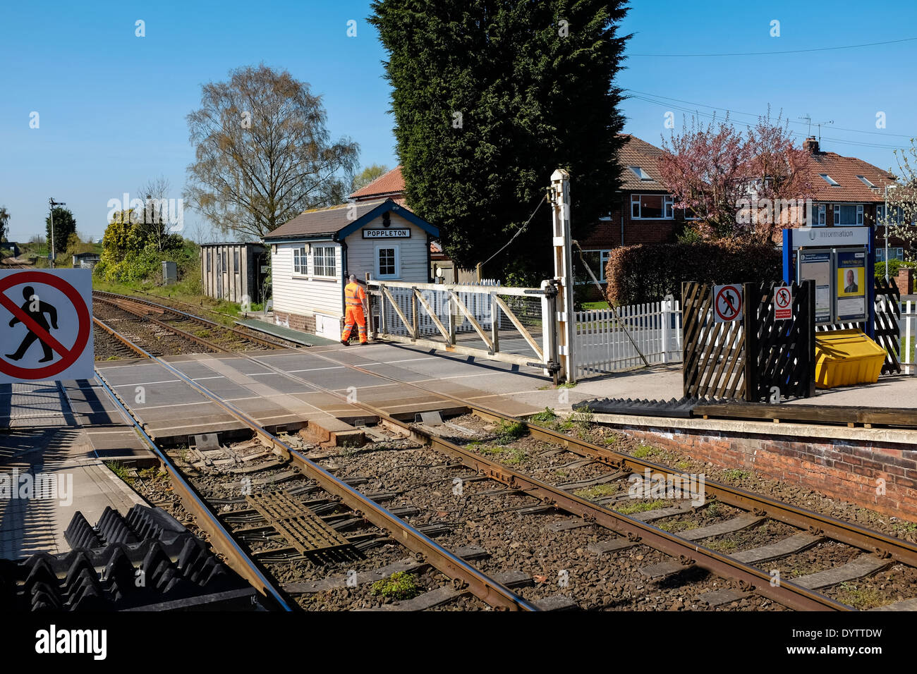 Poppleton station master securing a level crossing gate before a train arrives at the station on a sunny day. Stock Photo