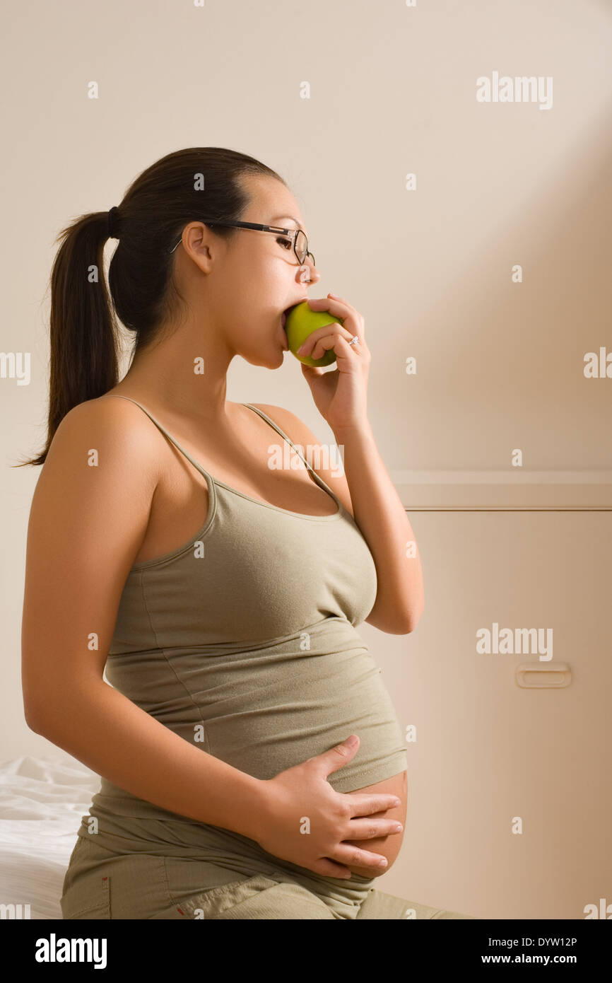 Expectant mother eating an apple Stock Photo
