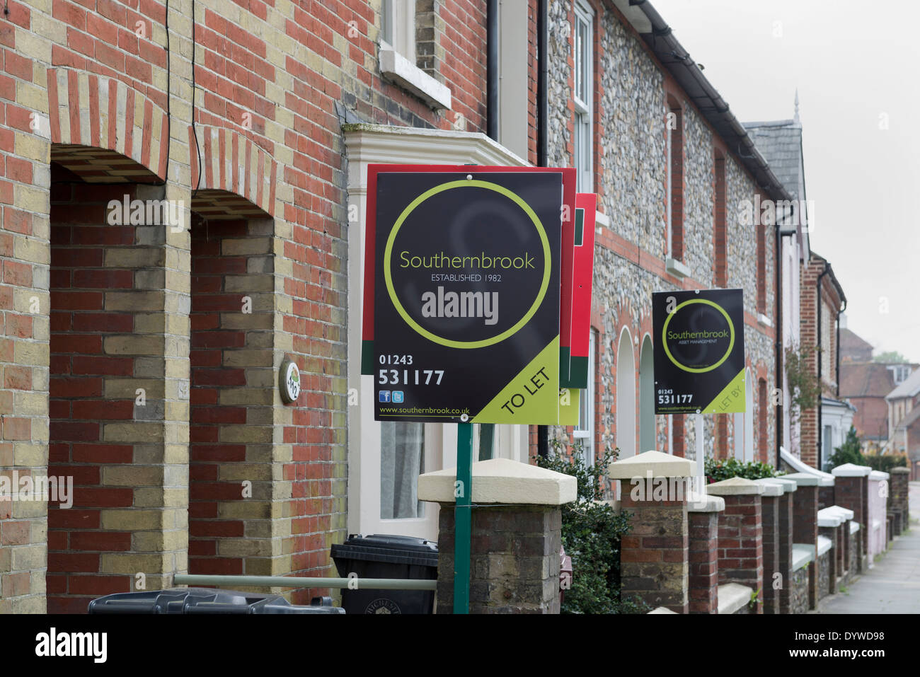 Street showing brick and flint built houses with To let signs in