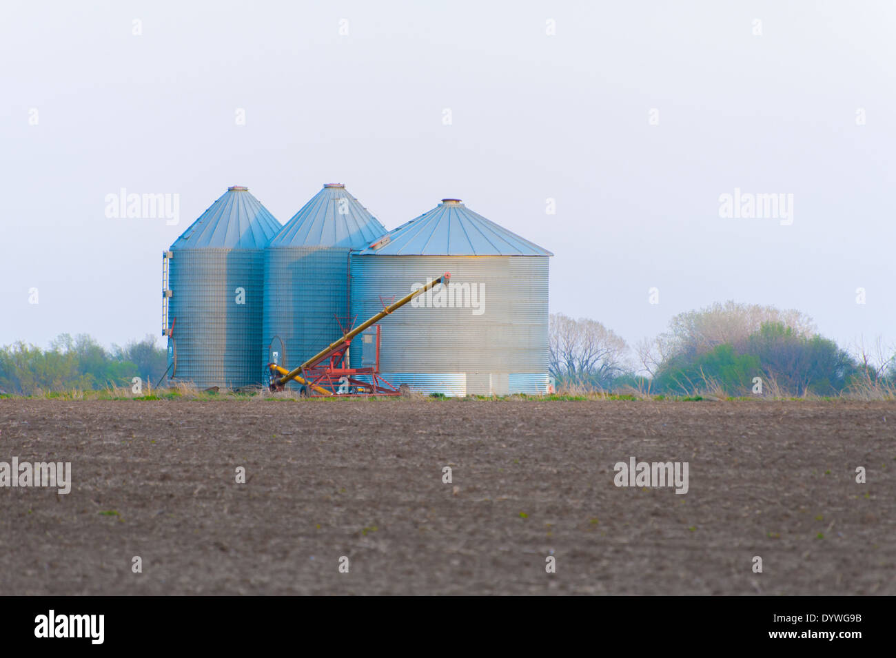 Grain bins with auger on the prairie at sunset Stock Photo