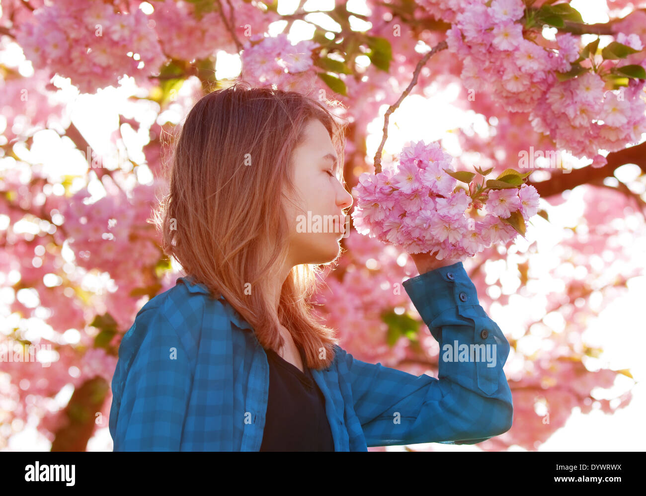 young girl smelling pink blossoms Stock Photo