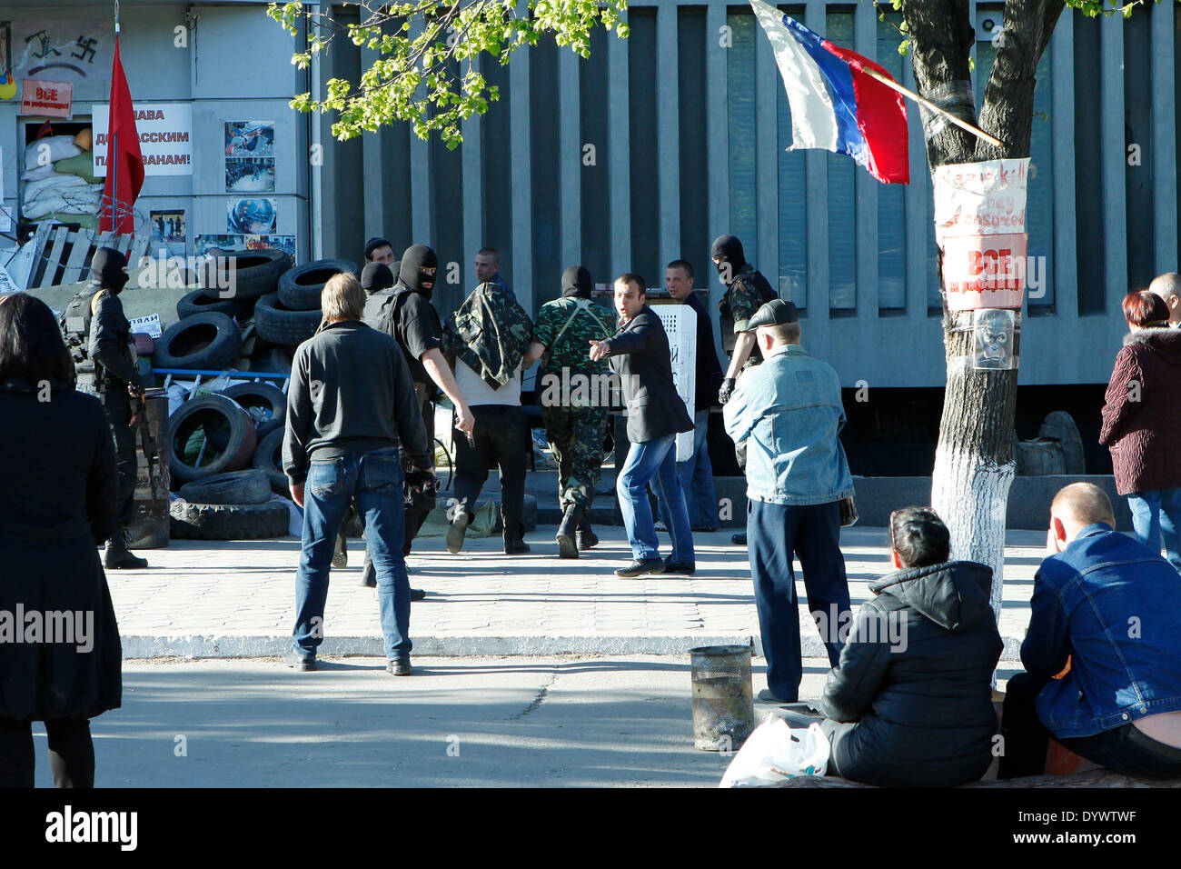 Luhansk, Ukraine. 25th Apr, 2014. EXCLUSIVE!!!: A man with covered head is brought into the building of secret office in Luhansk by 5 masked people and 1 man unmasked in blue jacket. The men in uniform have pistols and a sniper gun. Credit:  Cosimo Attanasio/Alamy Live News Stock Photo