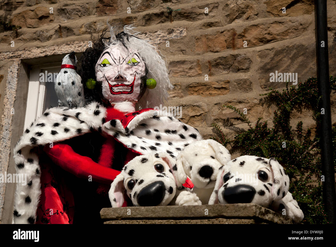 Evil 'Cruella De Vil' stuffed Evil Witch Evil Queen Maleficent. Caricature figure and her Dalmatian dogs at the Wray Scarecrow Festival established 1995, takes place every year, with a different theme. Stock Photo