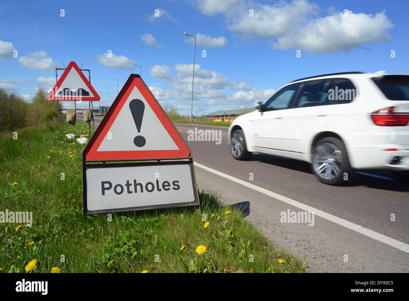 lorry passing pothole warning signs on road united kingdom Stock Photo