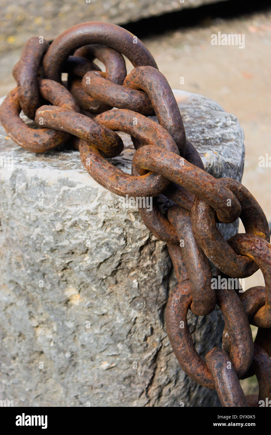 Thick chain links attached to bollard. Stock Photo