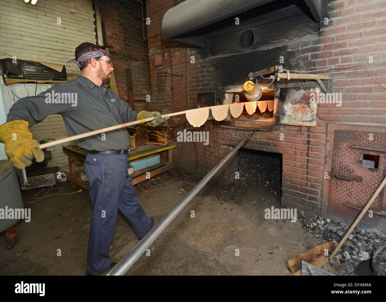 A religious Jewish man in a Matzoh bakery putting Matzoh onto an oven. Stock Photo