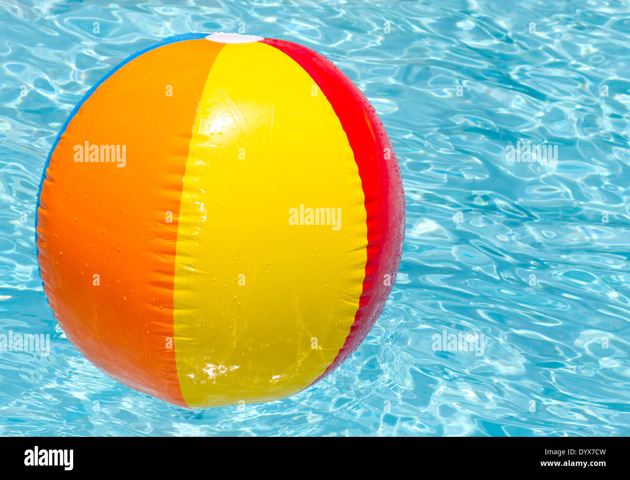 brightly coloured beach ball floating on clear blue water Stock Photo