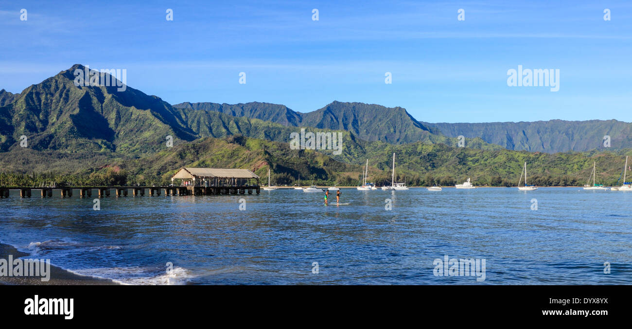 Stand-up paddlers by the Hanalei Pier in Hanalei Bay in Kauai Stock Photo