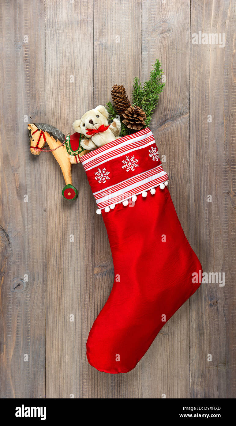 christmas stocking with nostalgic vintage toys decoration and pine branch over wooden background Stock Photo