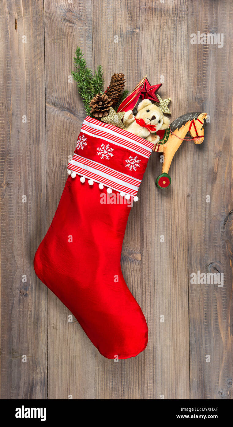 christmas stocking with nostalgic vintage toys decoration and pine branch over wooden background Stock Photo