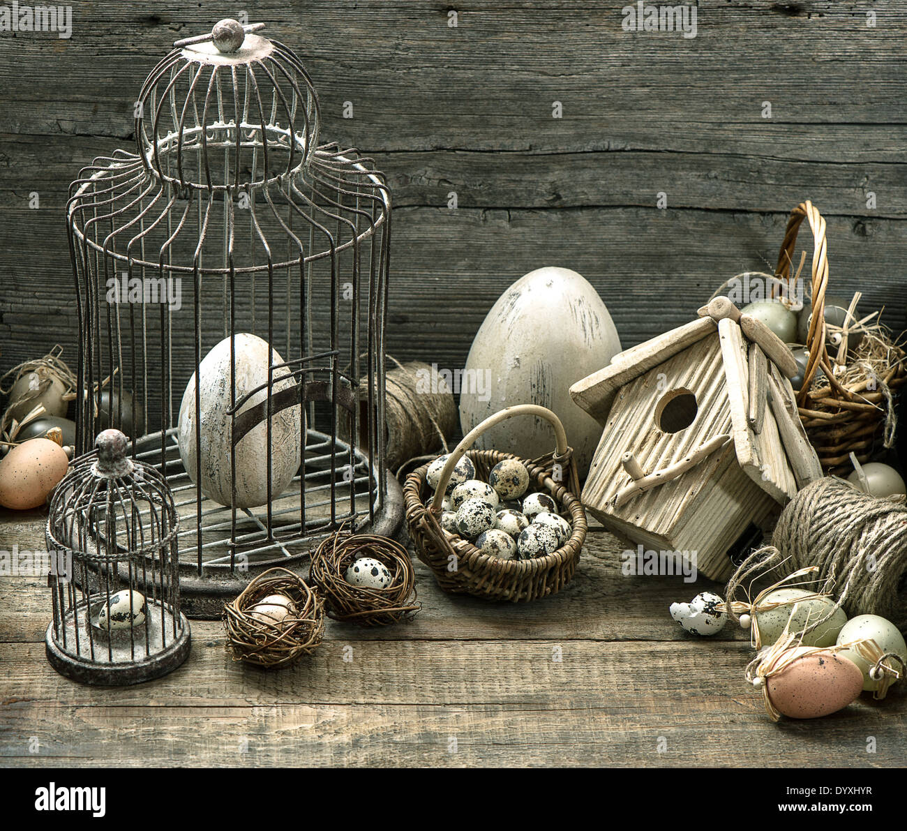 vintage easter decoration with eggs, birdhouse and birdcage. nostalgic still life home interior. wooden background Stock Photo