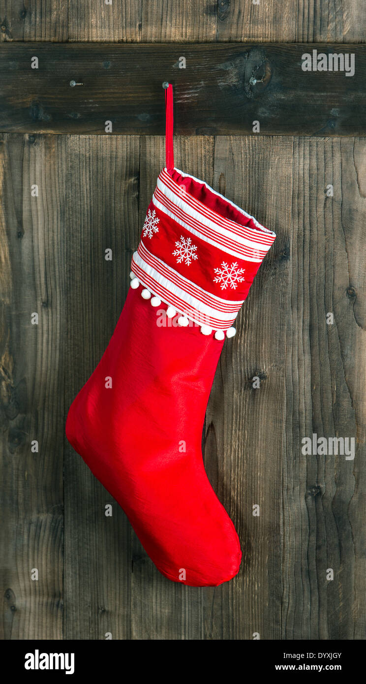 red sock with snowflakes for Santa gifts hanging over rustic wooden background. christmas stocking Stock Photo