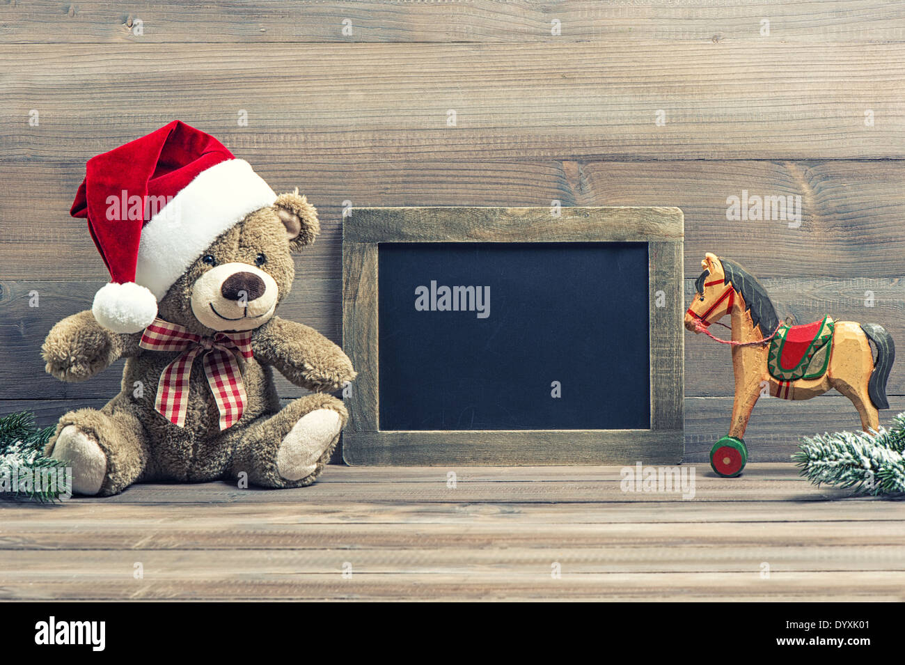 nostalgic christmas decoration with antique toys teddy bear and wooden rocking horse. vintage style picture with blackboard for Stock Photo
