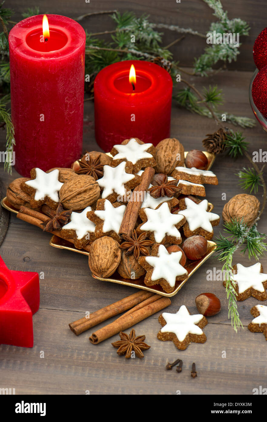 cinnamon cookies, nuts and spieces with christmas decoration red candles and pine branch. nostalgic home interior Stock Photo