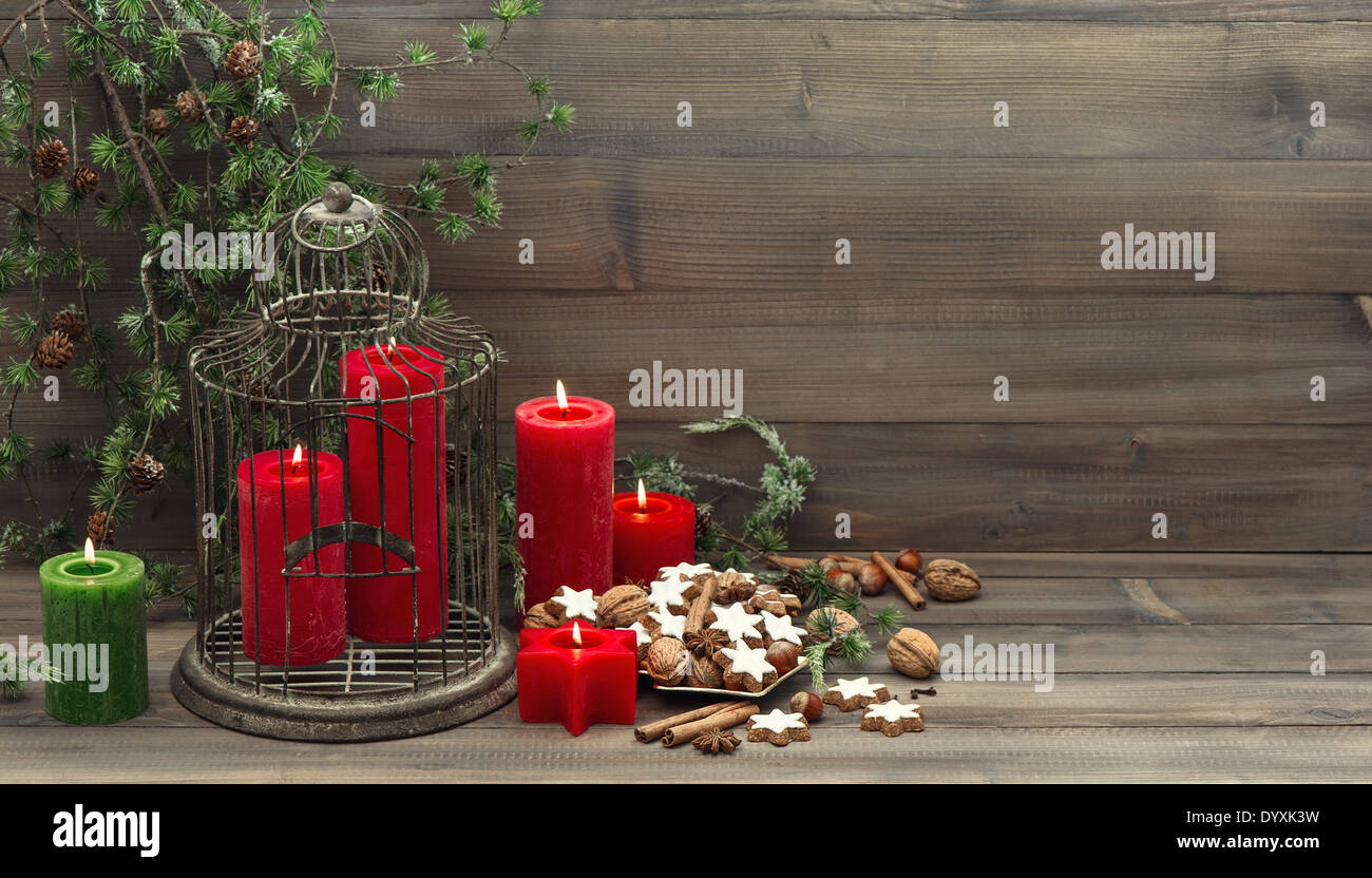 vintage christmas decoration birdcage, red candles and pine branch. nostalgic home interior. cinnamon cookies, nuts and spieces Stock Photo