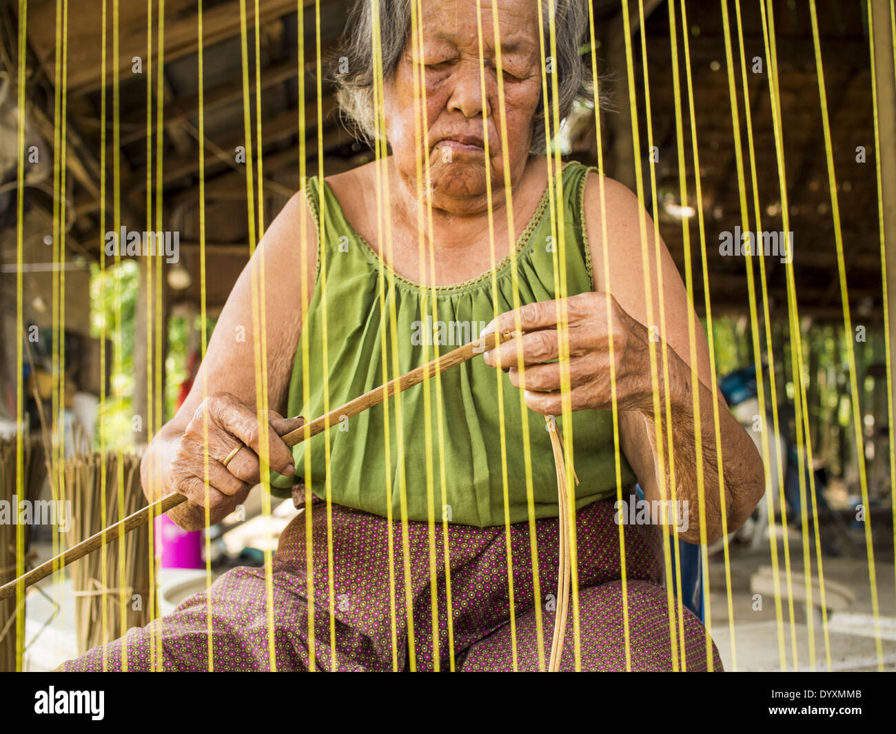 April 25, 2014 - Mae Chan, Chiang Rai, Thailand - An elderly woman weaves papyrus reed matts by hand at her family home in Mae Chan, Chiang Rai province, Thailand. Families in Chiang Rai province still make woven reed mats by hand. The mats are used around the house as an impromptu table, and farmers as something to spread out on the ground during lunch, like a picnic blanket. Some families use them as mattresses to sleep on. They cost anywhere from 15Baht (.50Â¢ US) to 150Baht ($5.00 US) depending on size. (Credit Image: © Jack Kurtz/ZUMAPRESS.com) Stock Photo
