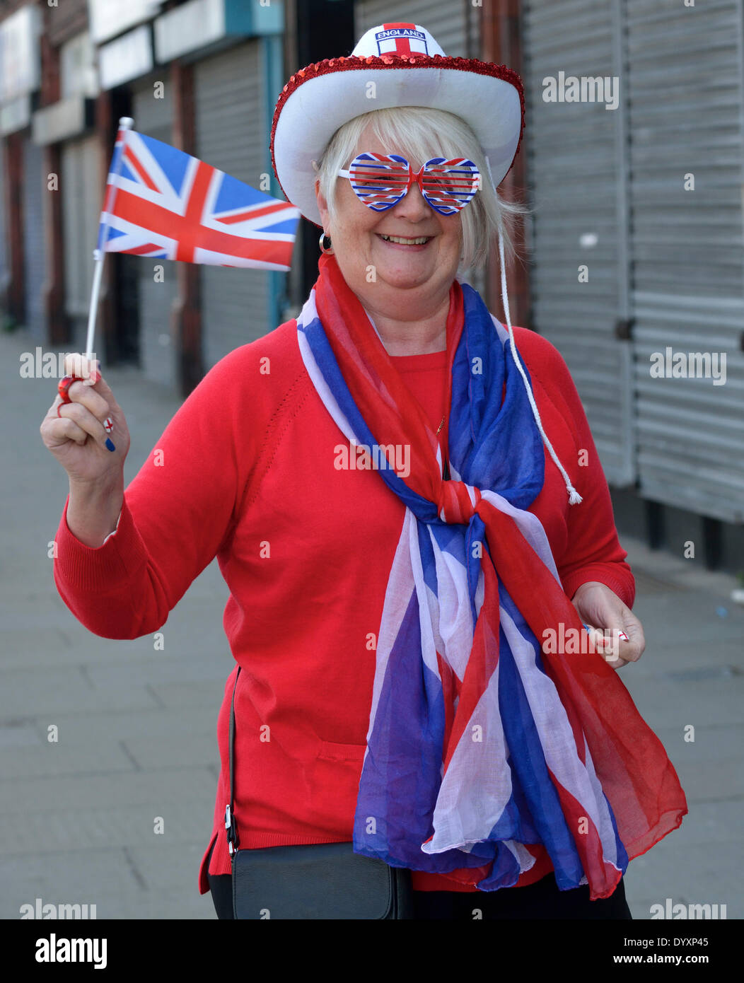 Manchester, UK. 27th Apr, 2014. Sixty-seven year old Linda Curran shows the England flag as she waits for the St George's Day Parade to pass along Oldham Road on its way through the centre of Manchester. St George's Day Parade  Manchester, UK  27th April 2014 Credit:  John Fryer/Alamy Live News Stock Photo