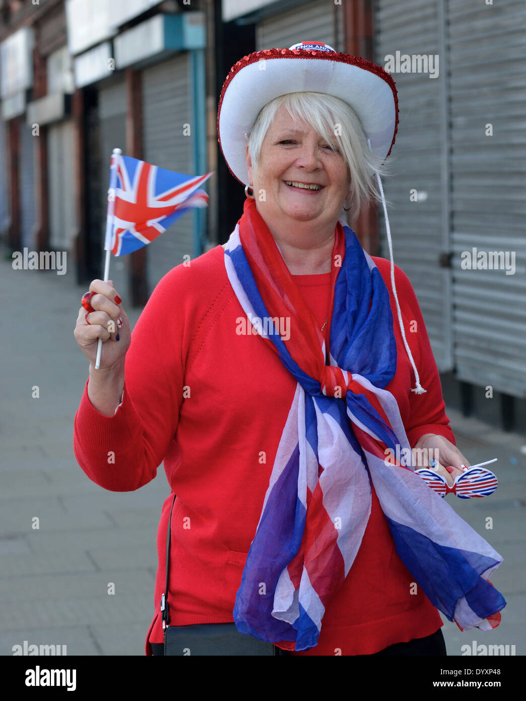 Manchester, UK. 27th Apr, 2014. Sixty-seven year old Linda Curran shows the England flag as she waits for the St George's Day Parade to pass along Oldham Road on its way through the centre of Manchester. St George's Day Parade  Manchester, UK  27th April 2014 Credit:  John Fryer/Alamy Live News Stock Photo