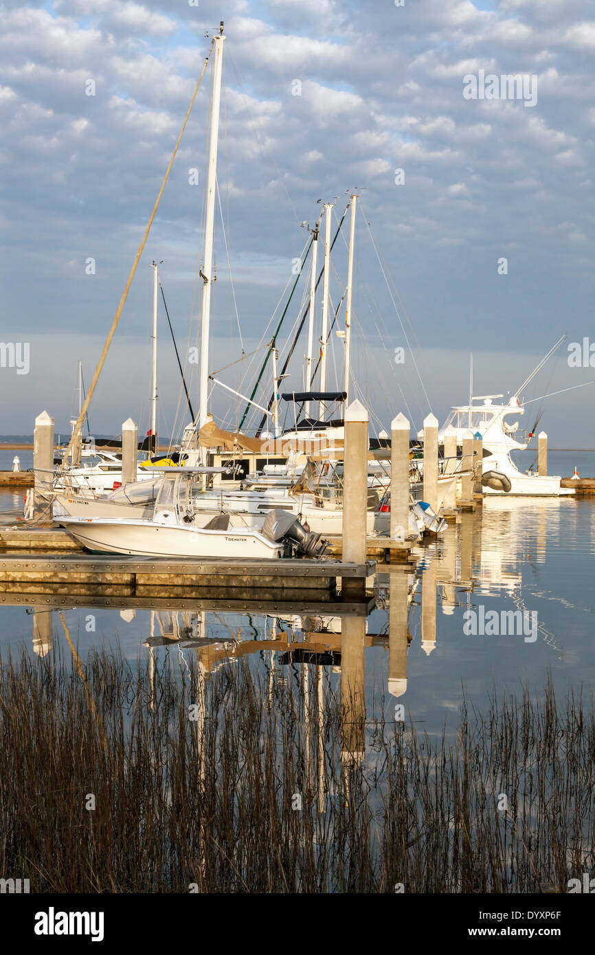 Fluffy white clouds (Altocumulus floccus) reflected in the dark water of the Fernandina Beach harbor and boat docks, USA. Stock Photo