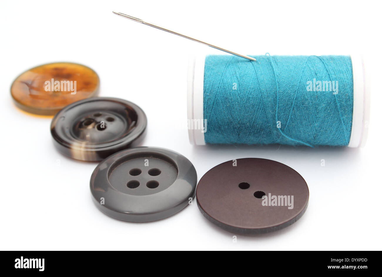Closeup of sewing buttons and spool of thread with needle. Isolated on ...