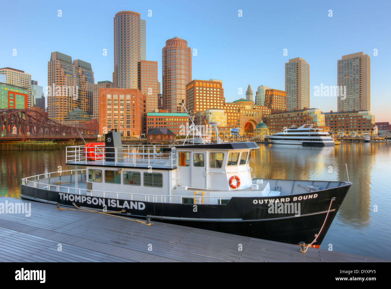 The Outward Bound Thompson Island Ferry sits docked in front of the skyline at sunrise in Boston, Massachusetts. Stock Photo