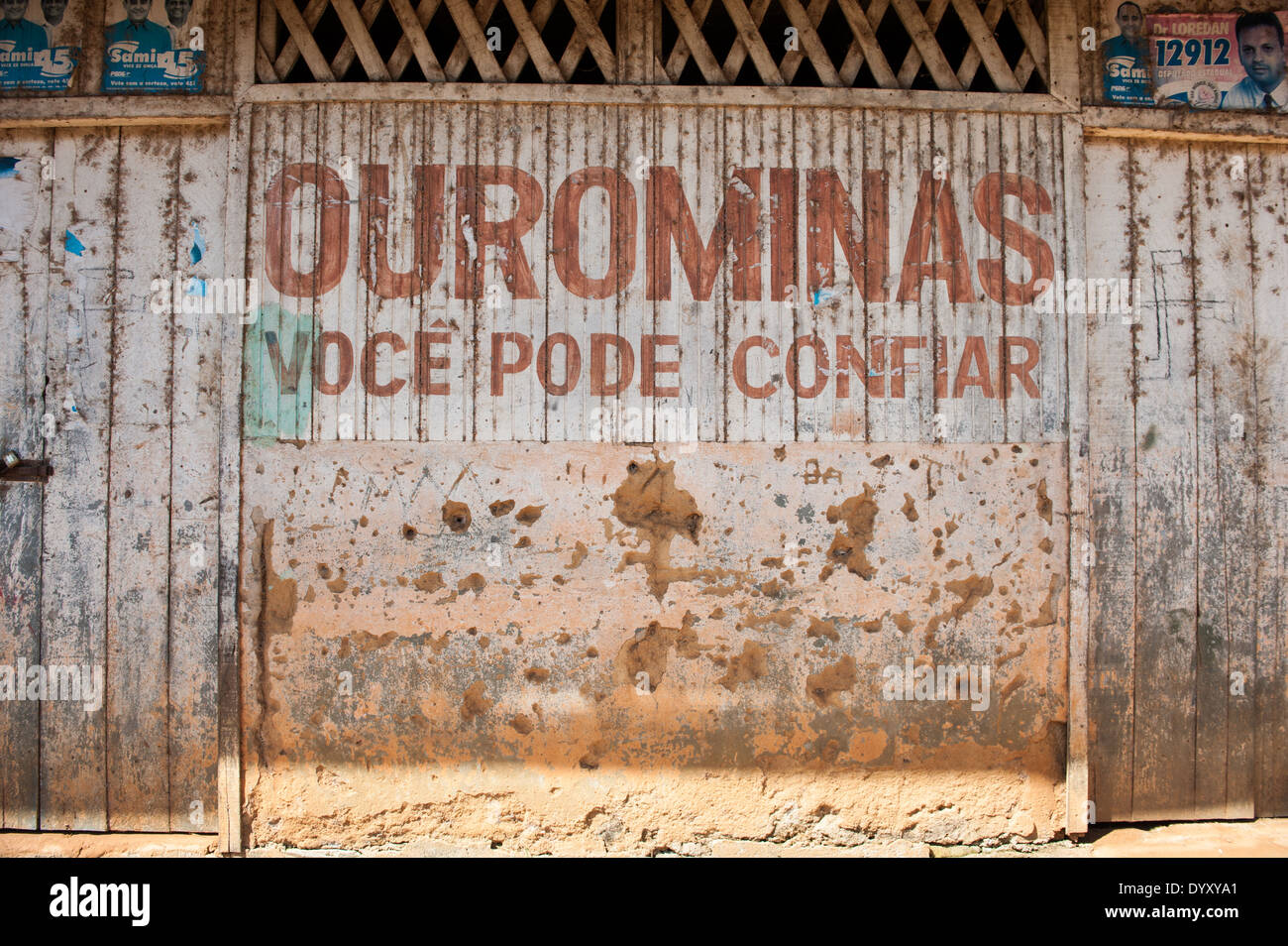 Xingu River, Para State, Brazil. The Volta Grande; Ressaca settlement, old garimeiro illegal gold-mining town. Bullet holes on the wall; the sign says 'Ourominas, you can trust'. Stock Photo
