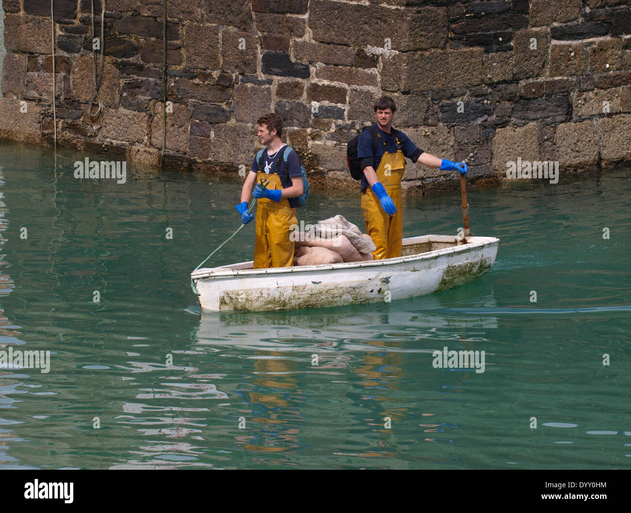 Two fishermen heading for shore in a dinghy using the one oar propulsion method, Newquay, Cornwall, UK Stock Photo