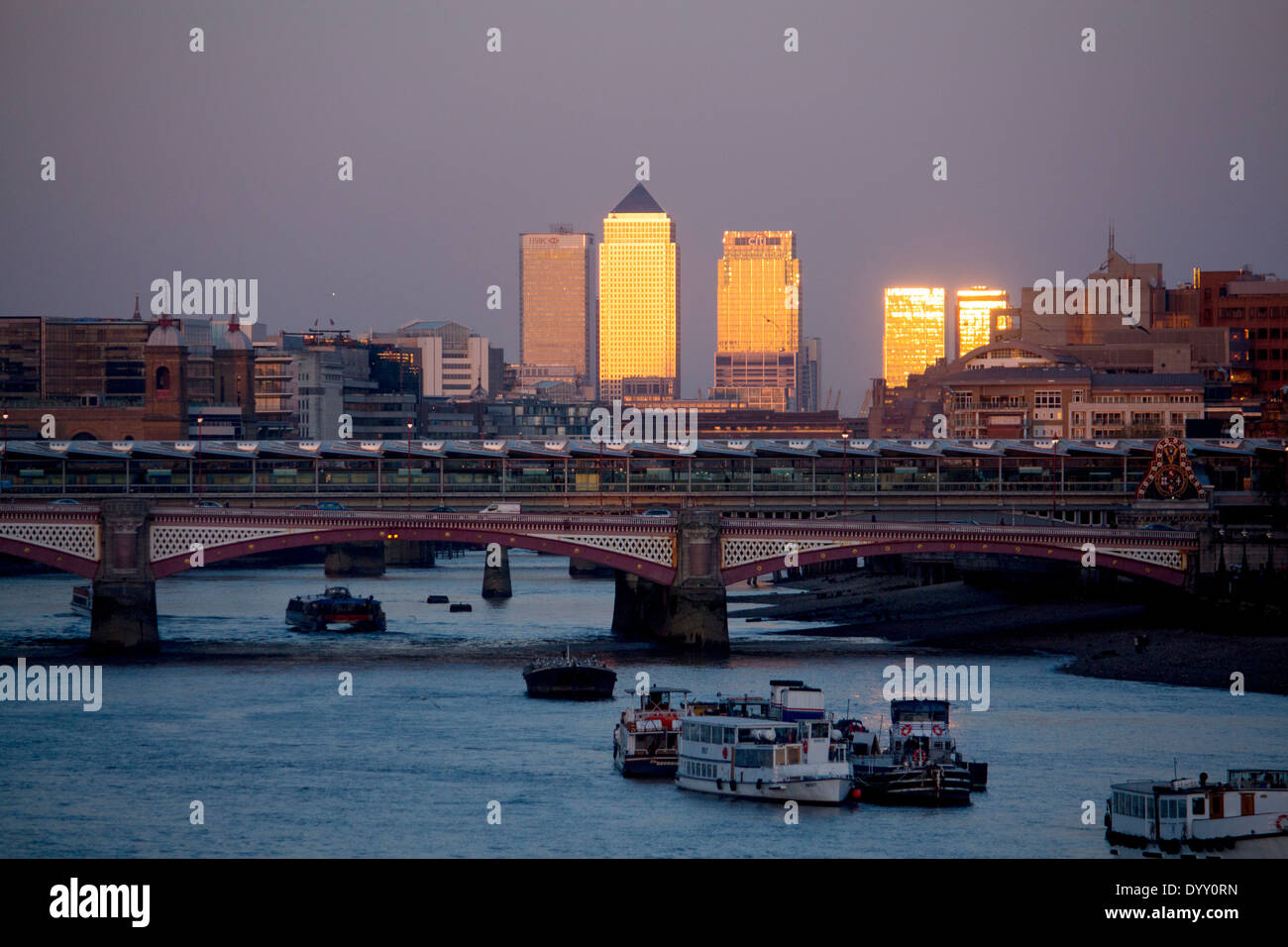 Canary Wharf towers at sunset from Waterloo bridge with River Thames and Blackfriars Bridge in foreground London England UK Stock Photo