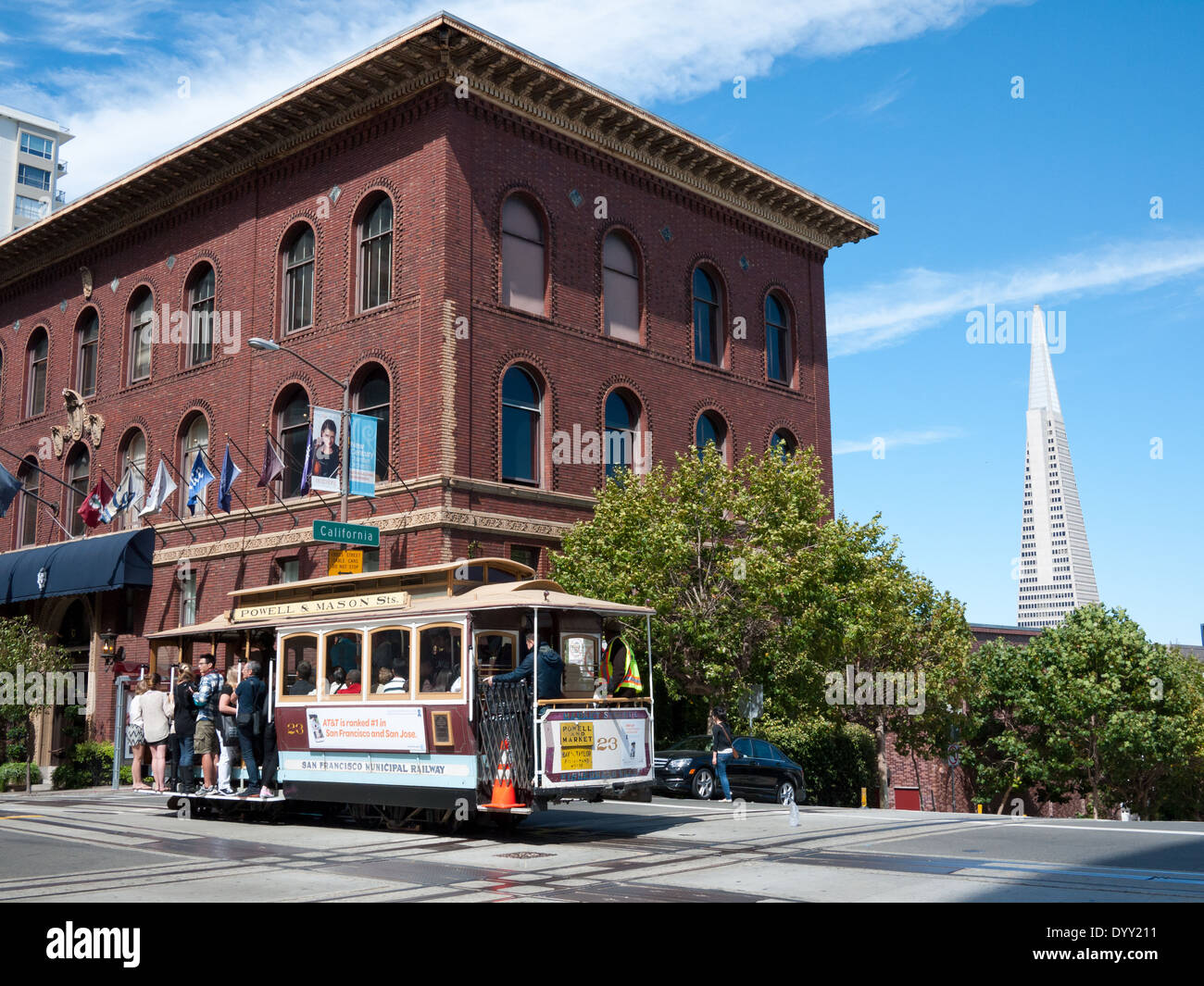 A Powell-Mason Cable Car passes the University Club of San Francisco, with the Transamerica Pyramid in the background. Stock Photo