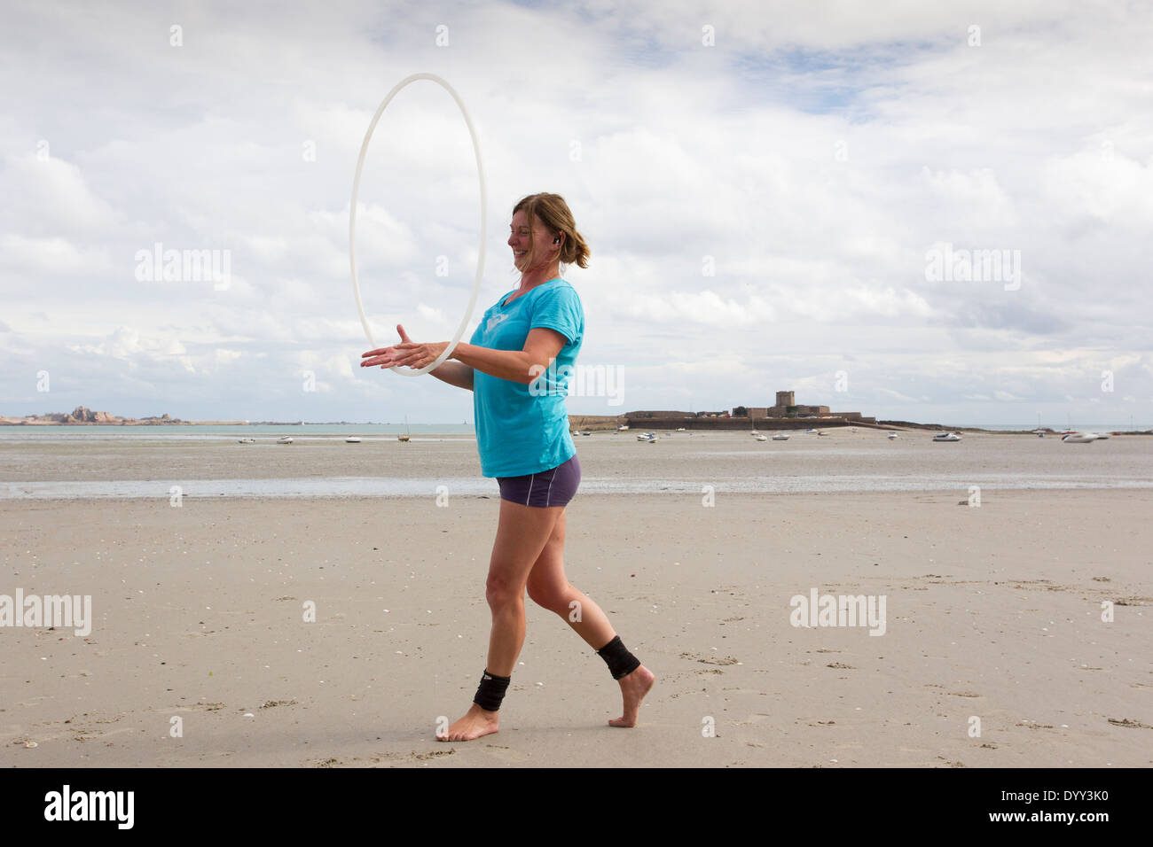 hula hoop work out exercise  on the beach in Jersey The Channel Islands Stock Photo