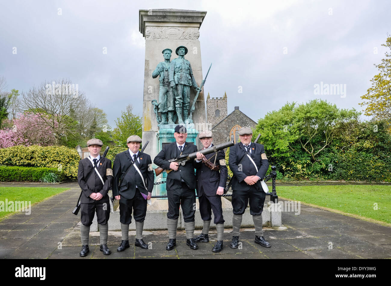 Five men carrying rifles, and one machine gun stand in front of a WW1 war memorial Stock Photo