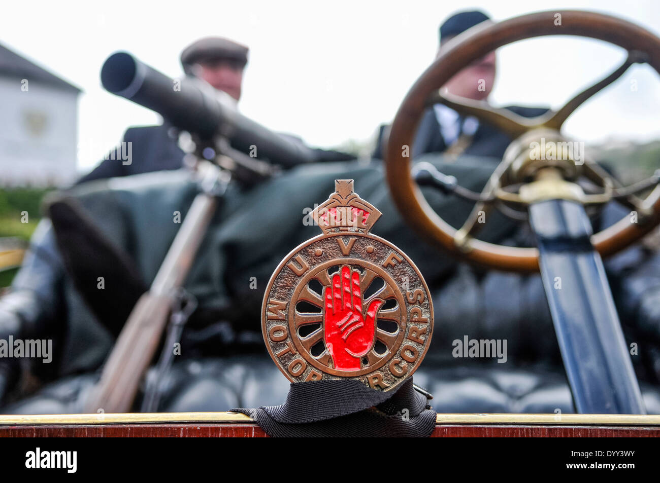 Badge of the UVF Motor Corps on the front of a classic car , with two men carrying guns Stock Photo