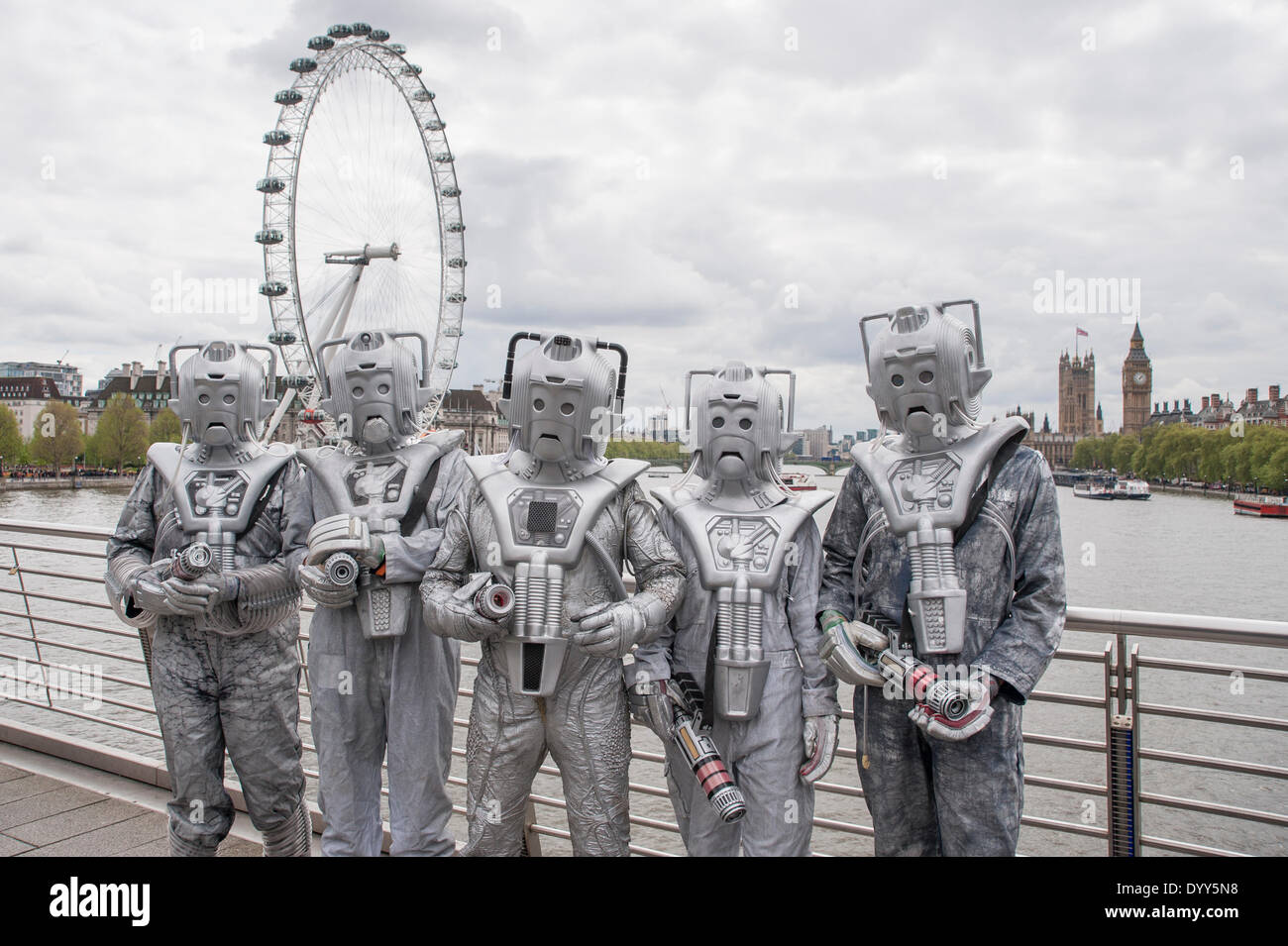 London, 27 April 2014 - people dressed as their favourite sci-fi characters take part in the Sci-Fi London 2014 costume parade starting at Somerset House and finishing at the BFI on the South Bank.  Cybermen on Hungerford Bridge, with the London Eye and Houses of Parliament in the distance.    Credit:  Stephen Chung/Alamy Live News Stock Photo