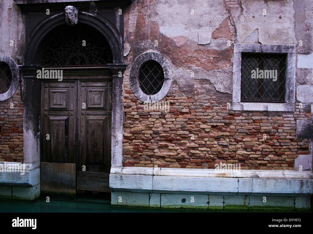 Rich colour and detail of an exposed brick wall and decaying plaster on a building in a Venice canal Stock Photo