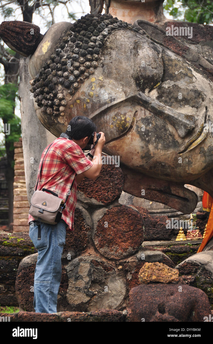 Traveler take a photo Buddha image at Kamphaeng Phet Historical Park Aranyik area,Buddha of thailand Stock Photo