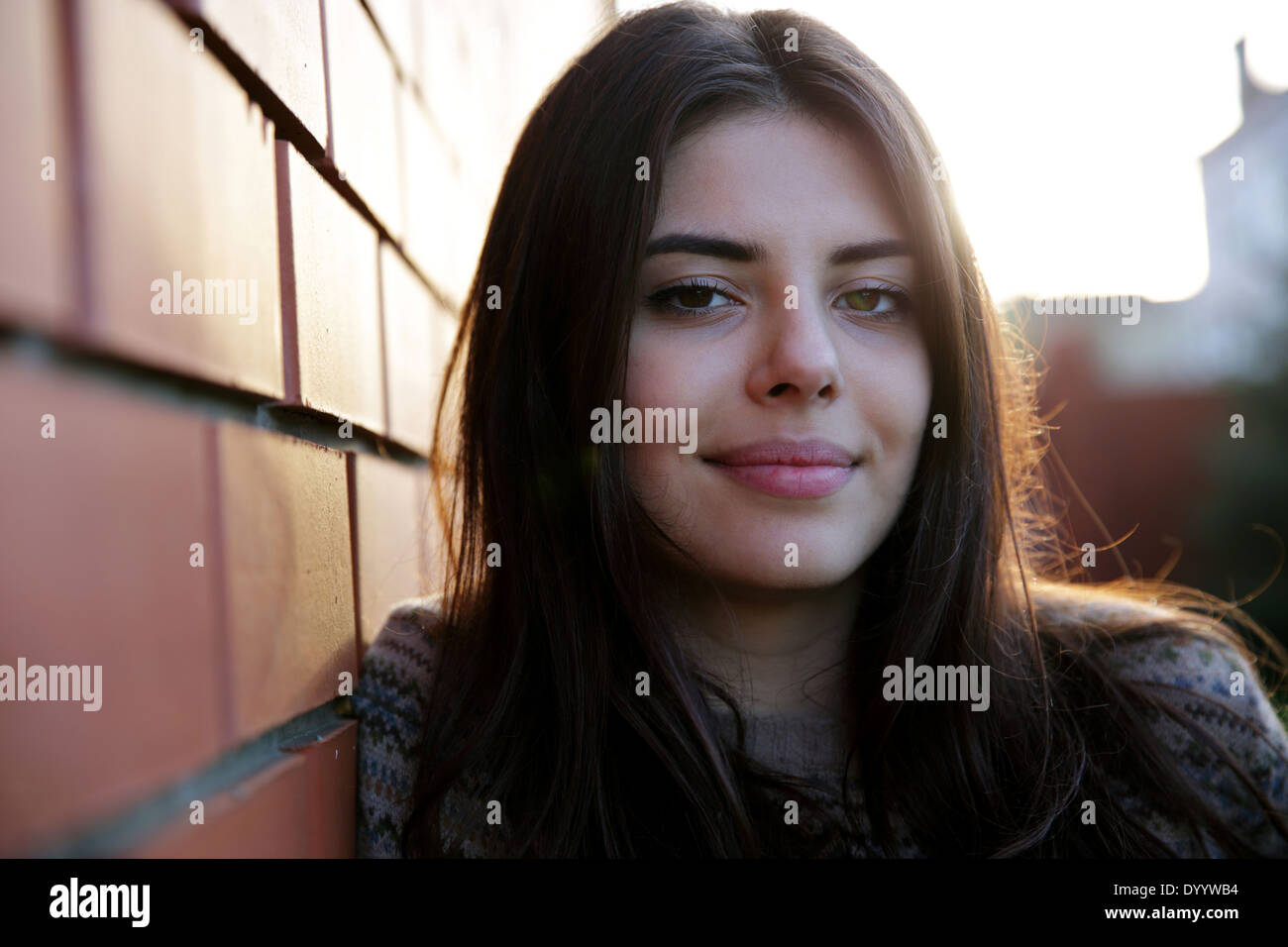 Beautiful smiling woman standing near brick wall Stock Photo - Alamy