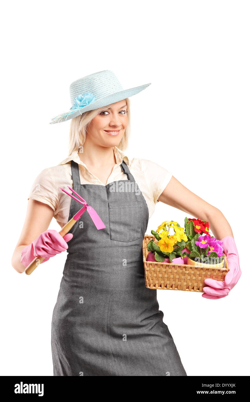 Female gardener holding a mattock and a basket with flowers Stock Photo