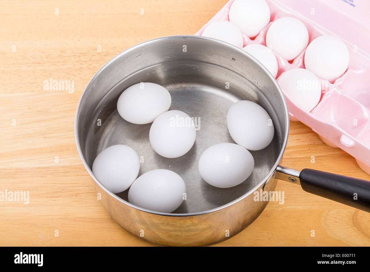 Six eggs in a saucepan of water with six more in an egg carton Stock Photo