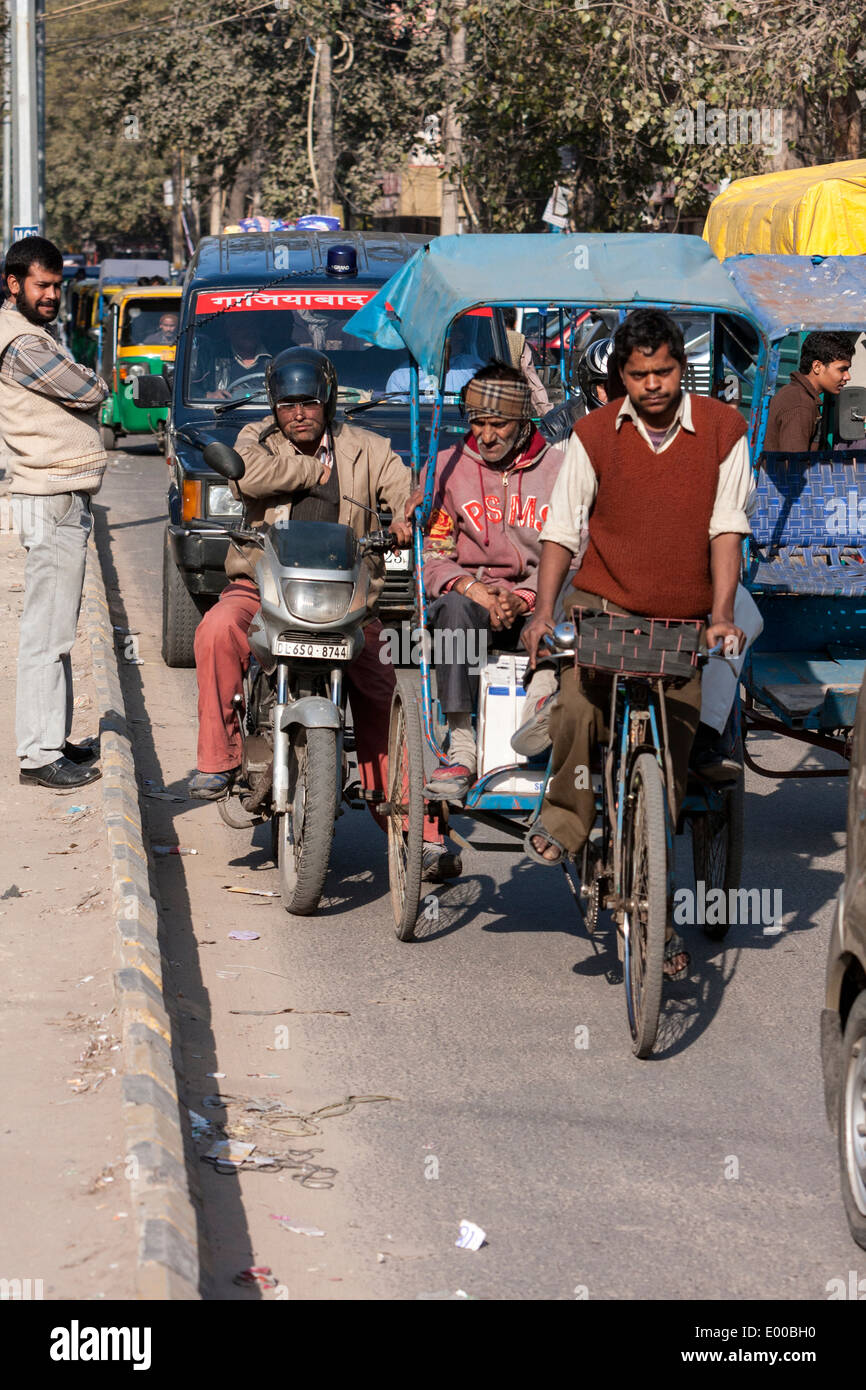 New Delhi, India. Rickshaw Driver and Passenger in Mid-day Delhi Traffic. Stock Photo