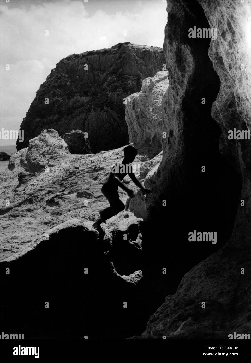 Boy climbs a rock on the island Ponza Stock Photo
