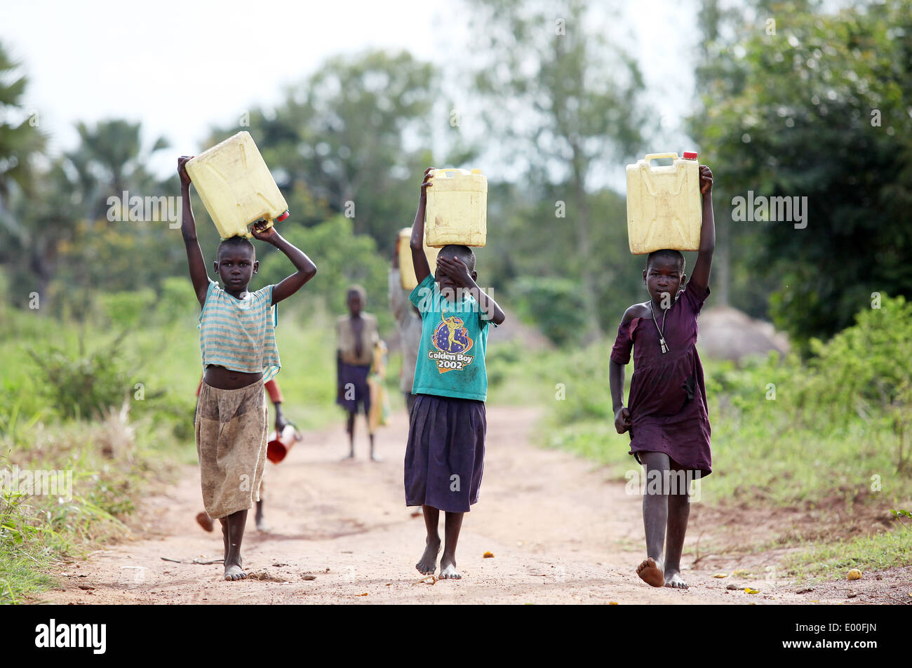 Young village children finish their day off by collecting dirty water for their families in the Lira district of northern Uganda Stock Photo