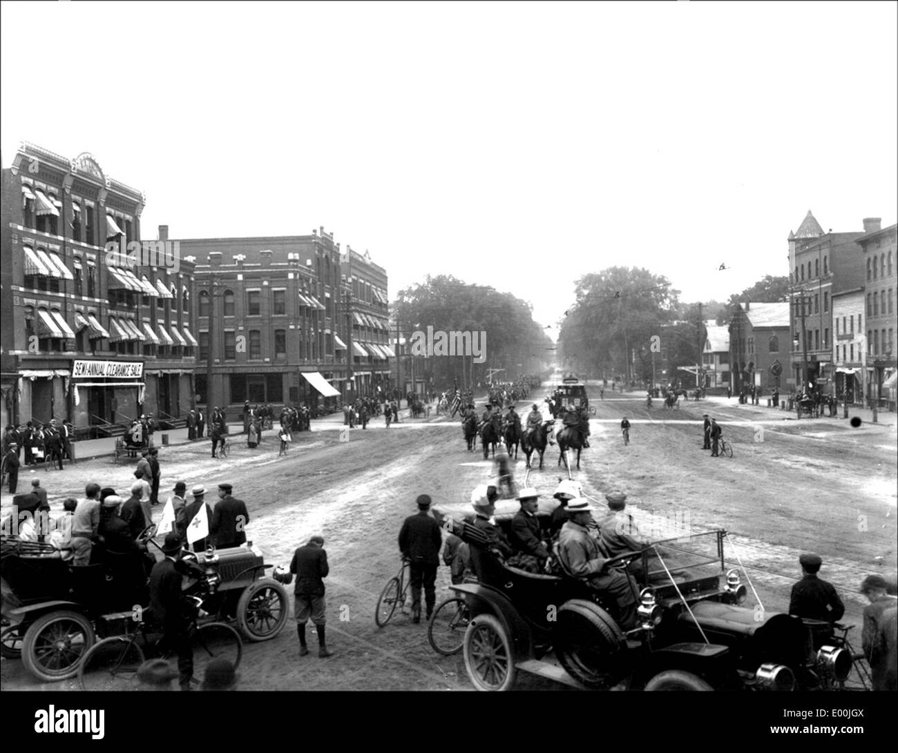 This historical photograph captures soldiers parading through Keene, New Hampshire, featuring antique cars, horses, and the business district. It reflects the town's cultural history and military tradition during the early 20th century. Stock Photo