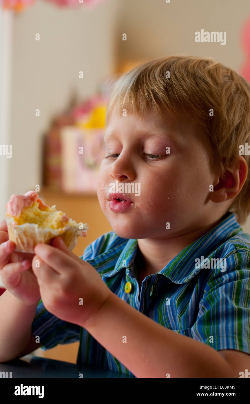 A little boy eating a cupcake at a birthday party Stock Photo - Alamy