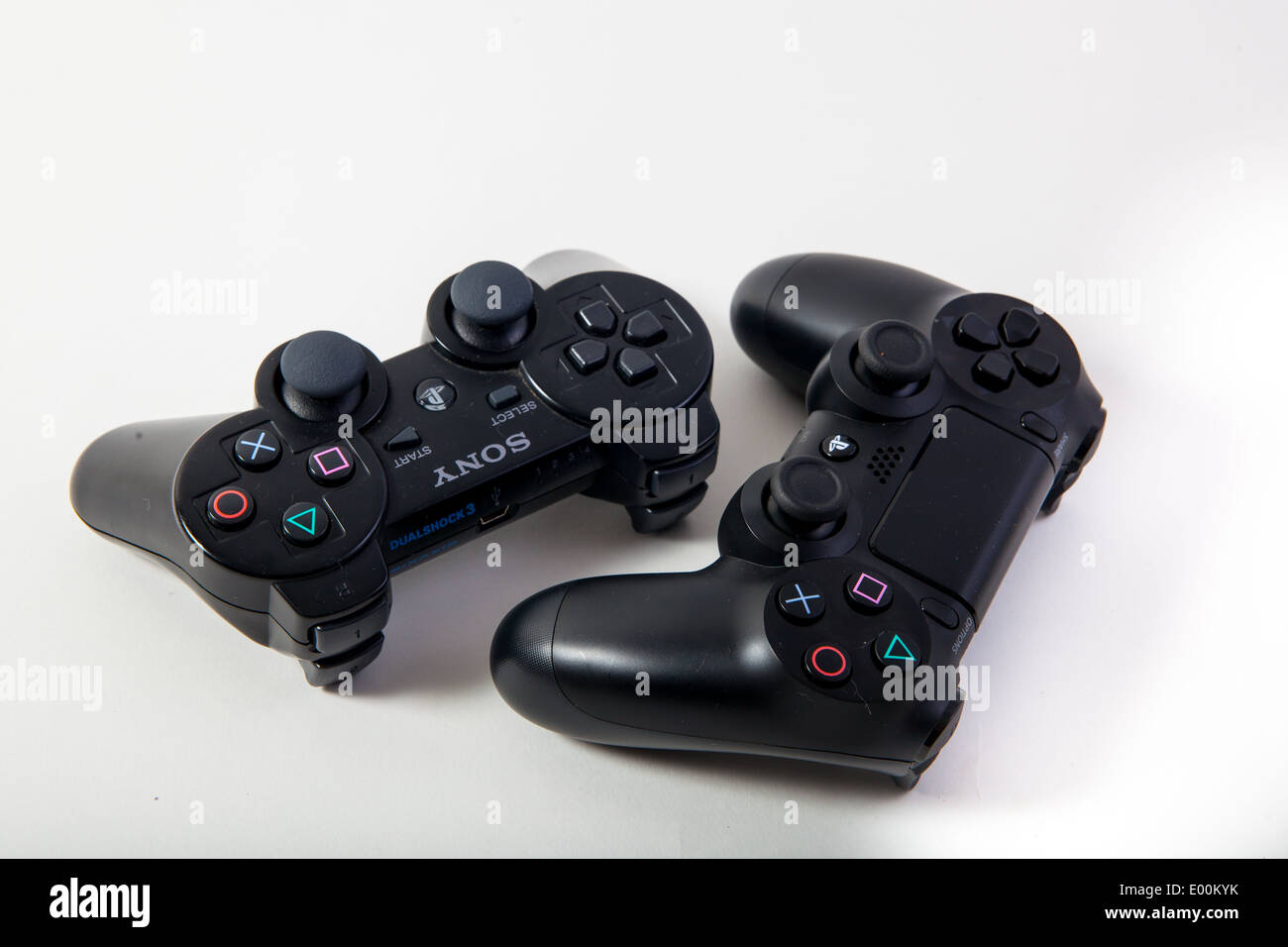 Sony Playstation 3 and 4 original authentic black gaming controllers on a white studio background. Stock Photo