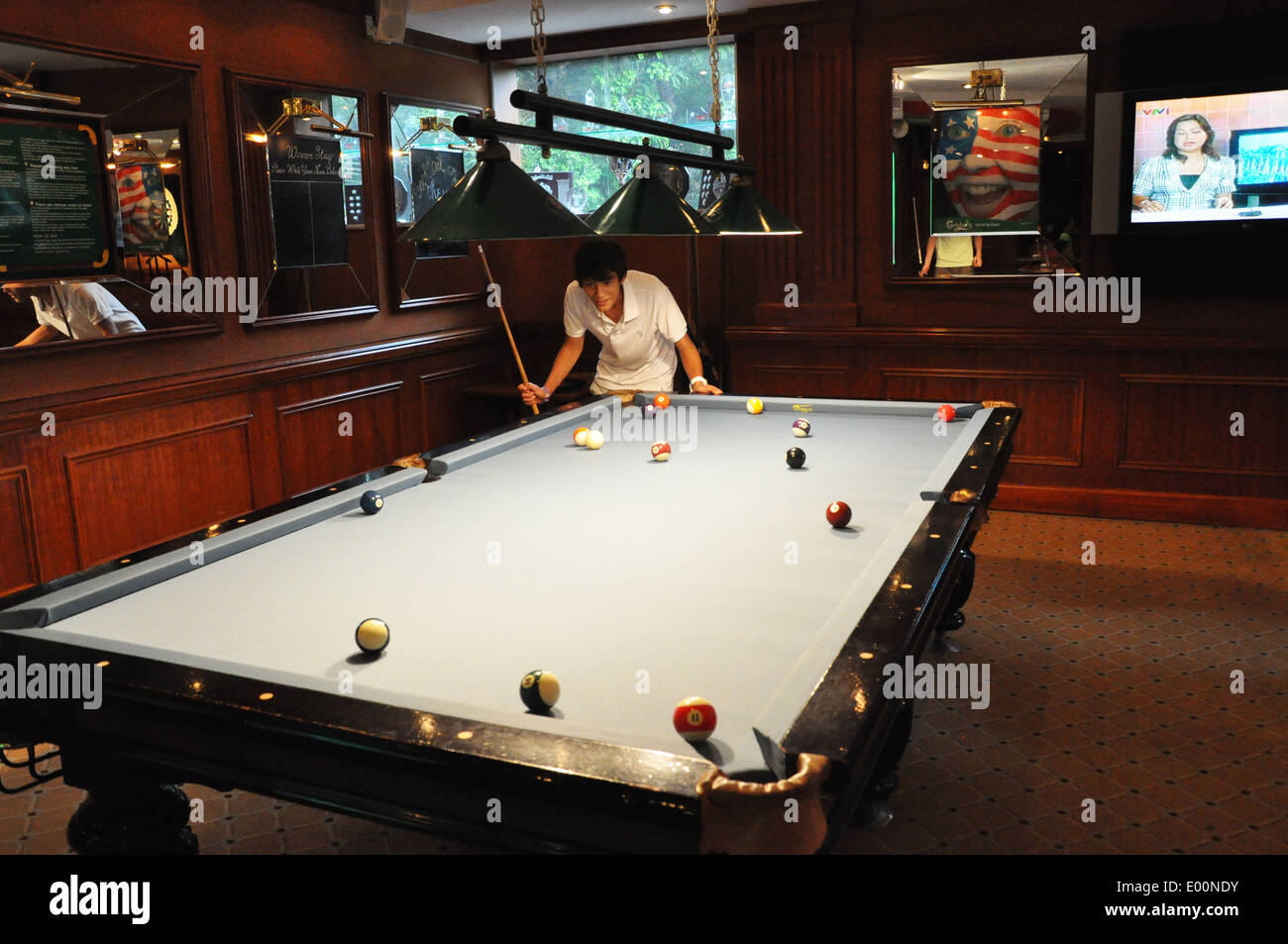 A teenage boy plays pool in the bar of the Hilton Hanoi Opera Hotel in Hanoi, Vietnam Stock Photo