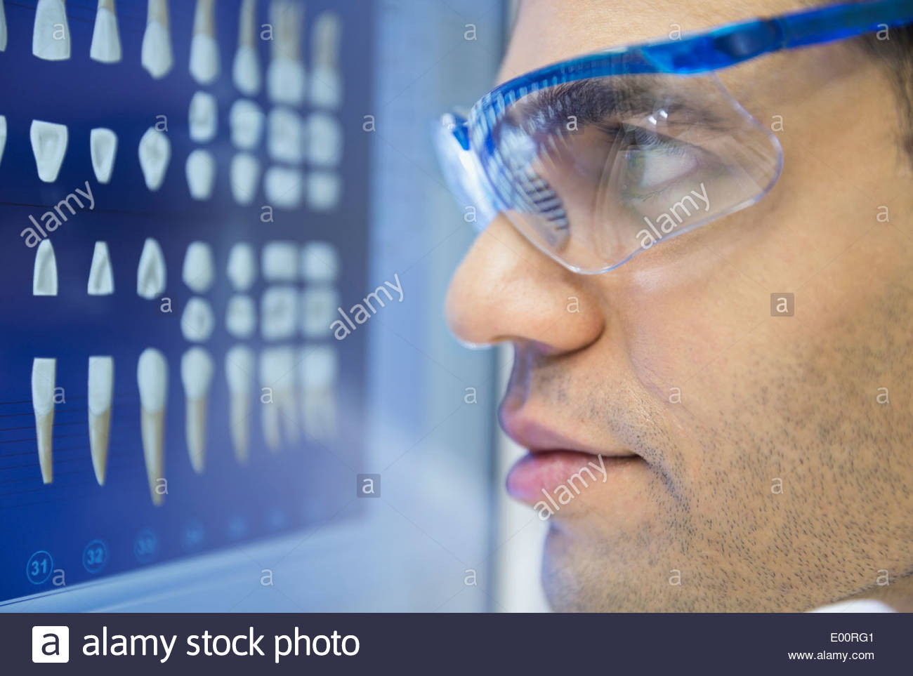 Focused dentist in goggles examining tooth x-rays Stock Photo - Alamy