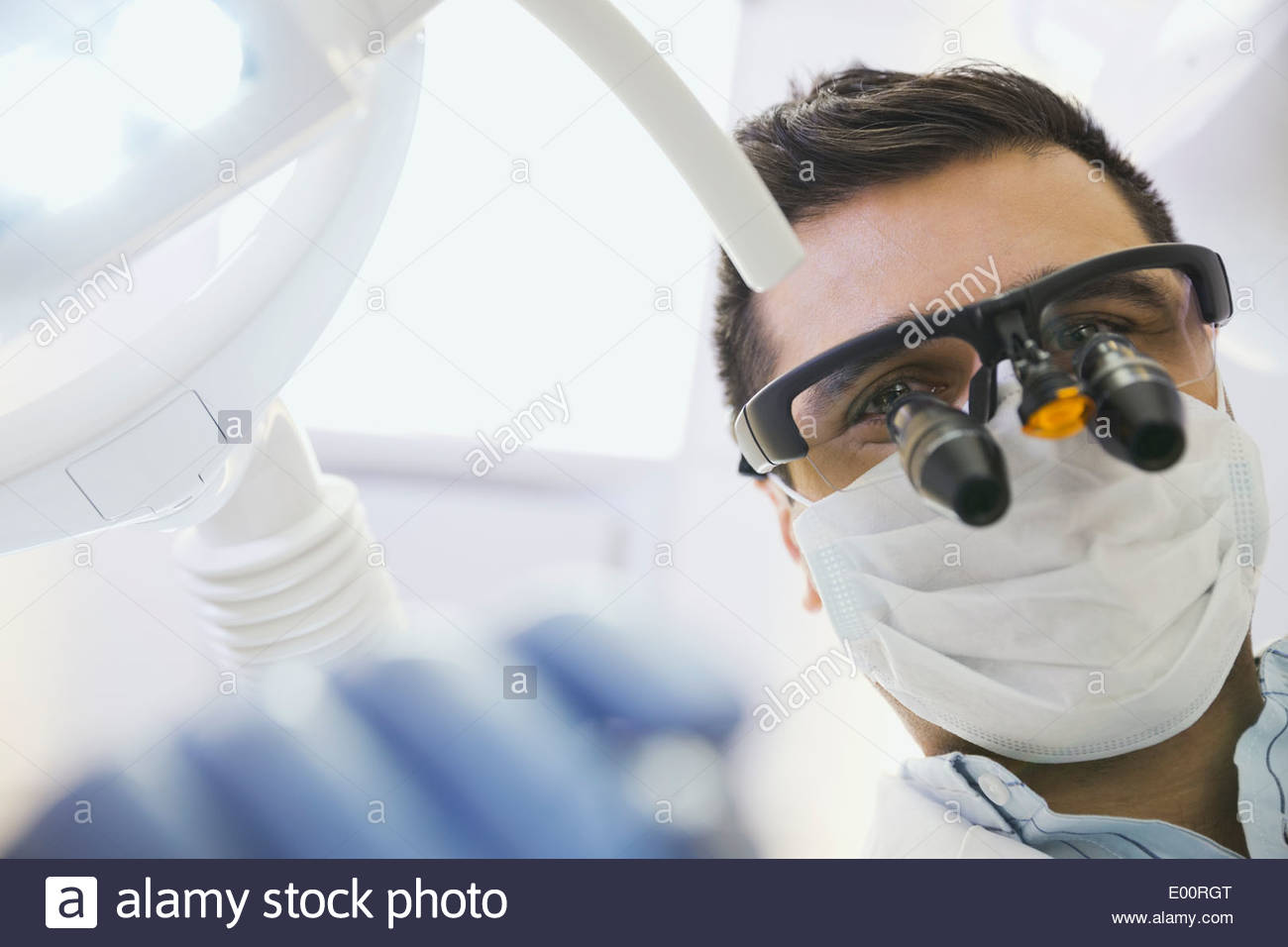 Dentist in dental loupes performing checkup Stock Photo