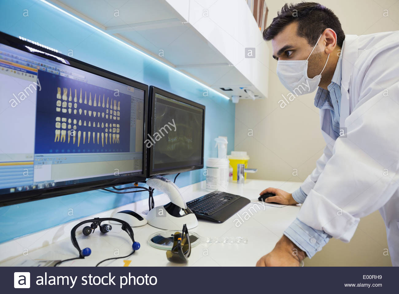Dentist in surgical mask reviewing tooth x-rays Stock Photo