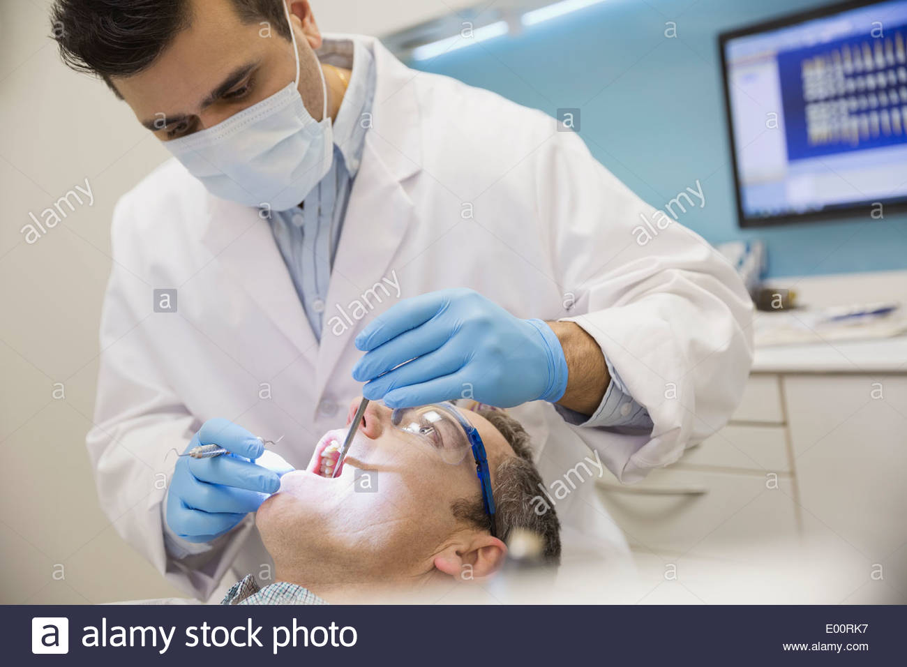 Dentist in surgical mask examining patients mouth Stock Photo